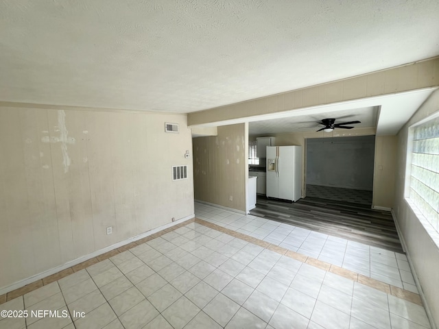 spare room featuring a ceiling fan, visible vents, a textured ceiling, and light tile patterned floors