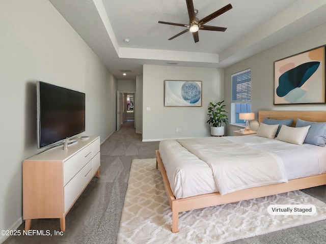 bedroom featuring ceiling fan, a tray ceiling, light colored carpet, and baseboards