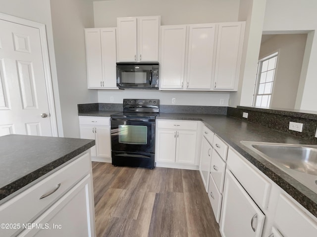 kitchen with black appliances, dark countertops, and white cabinets