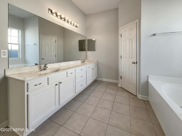 full bath with double vanity, baseboards, tile patterned floors, a garden tub, and a sink