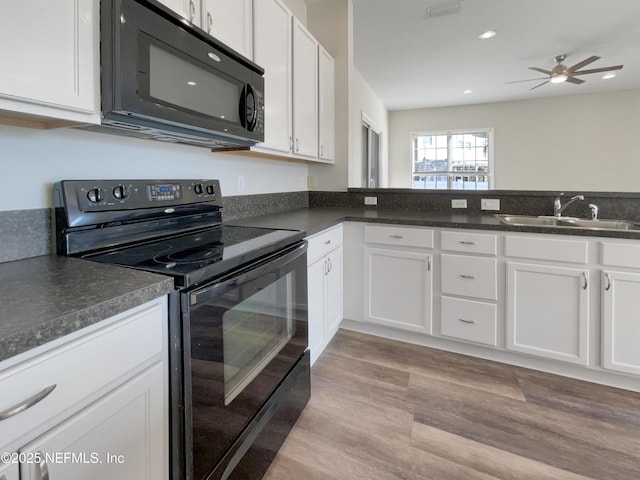 kitchen with black appliances, dark countertops, a sink, and white cabinets