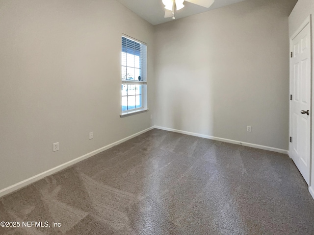 unfurnished room with baseboards, dark carpet, and ceiling fan