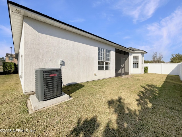 back of house with cooling unit, a fenced backyard, a lawn, and stucco siding