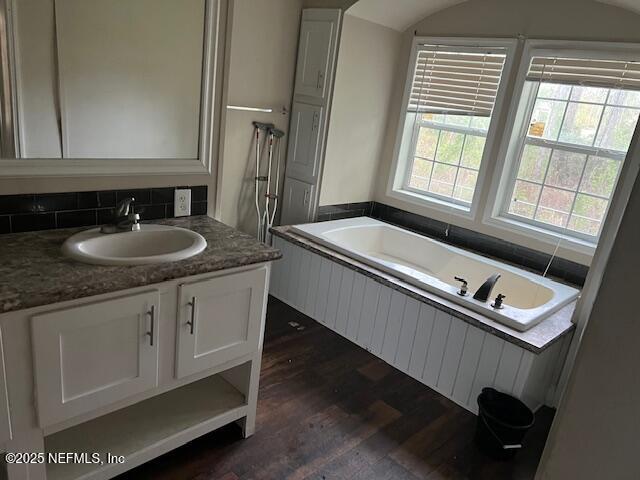 full bathroom with a garden tub, wood finished floors, and vanity