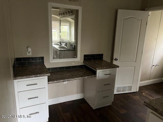 kitchen with white cabinetry, dark stone counters, visible vents, and dark wood-style flooring