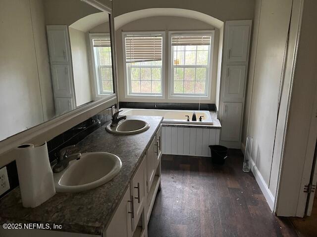 full bathroom featuring a sink, a bathtub, double vanity, and hardwood / wood-style flooring