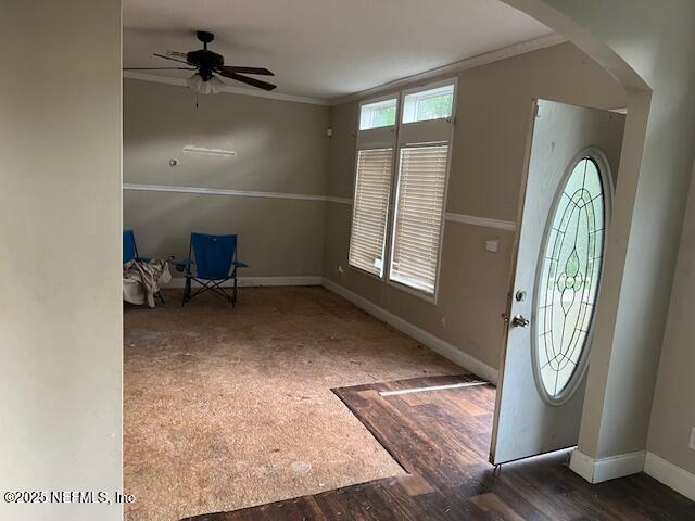 entryway with ceiling fan, wood finished floors, baseboards, and ornamental molding