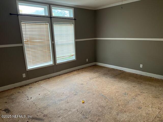 spare room with a healthy amount of sunlight, baseboards, and ornamental molding