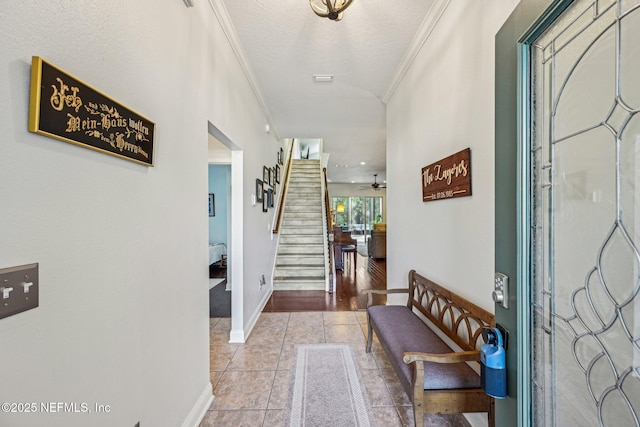 foyer featuring crown molding, baseboards, stairs, light tile patterned floors, and a textured ceiling