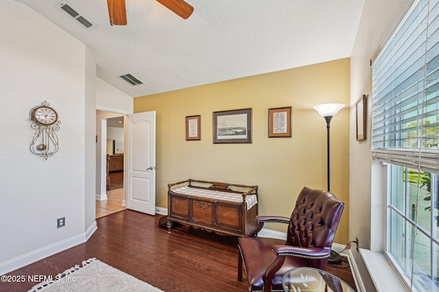 living area with visible vents, wood finished floors, baseboards, and ceiling fan