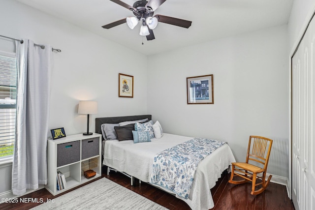 bedroom with a closet, baseboards, dark wood-type flooring, and ceiling fan