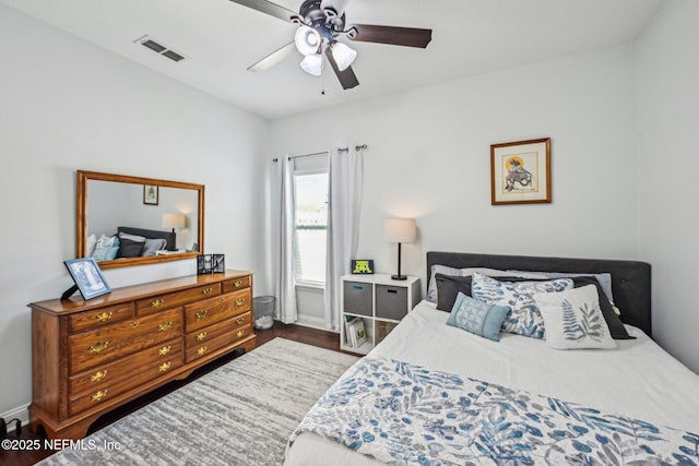 bedroom with visible vents, baseboards, wood finished floors, and a ceiling fan