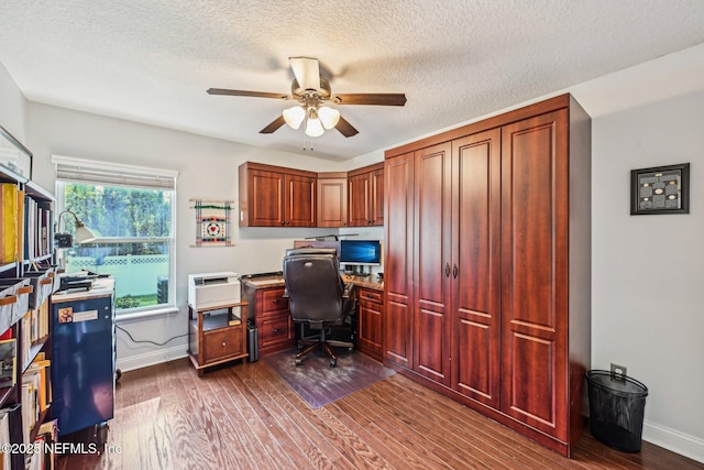 home office featuring baseboards, dark wood-type flooring, a ceiling fan, and a textured ceiling