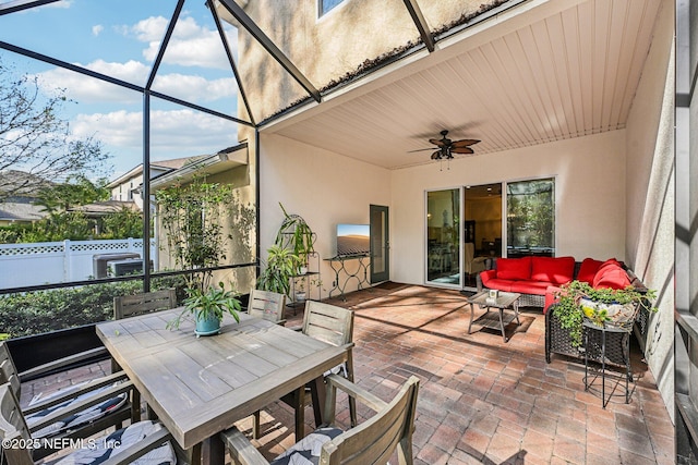 view of patio with ceiling fan, fence, glass enclosure, an outdoor hangout area, and outdoor dining space