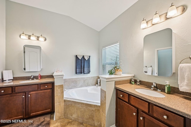 full bath with two vanities, vaulted ceiling, a bath, and a sink