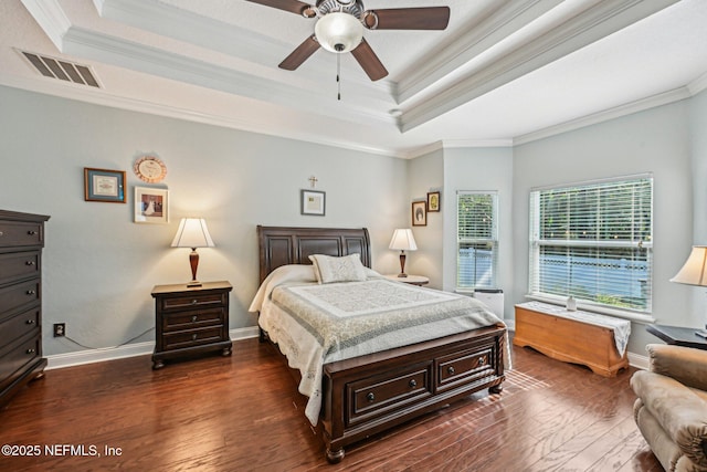 bedroom with visible vents, baseboards, dark wood finished floors, a tray ceiling, and crown molding