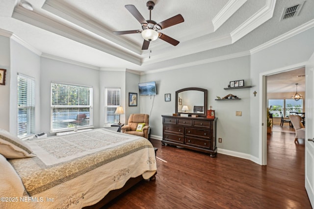 bedroom with a tray ceiling, dark wood-style floors, visible vents, and ornamental molding