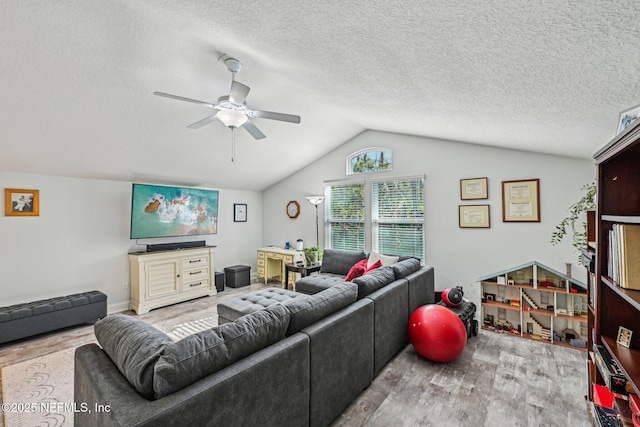 living room featuring vaulted ceiling, a textured ceiling, ceiling fan, and wood finished floors