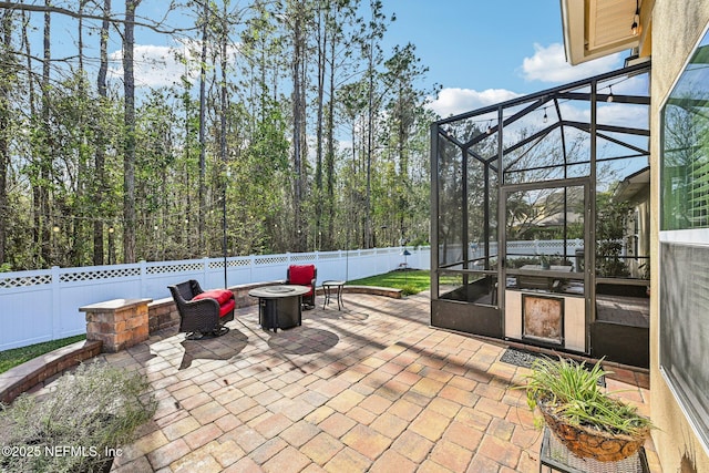 view of patio / terrace with a lanai, a fenced backyard, and an outdoor fire pit