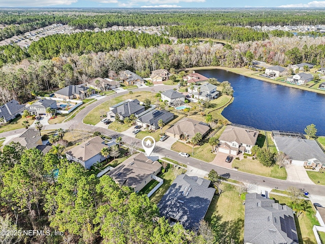 drone / aerial view featuring a wooded view, a residential view, and a water view