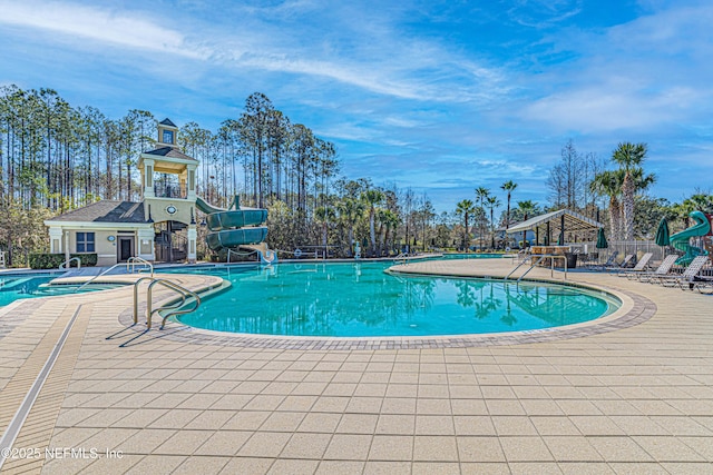 pool featuring a patio area, fence, and a water slide