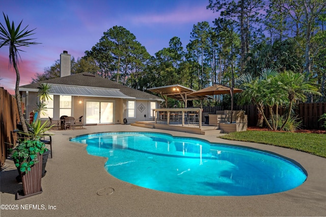 pool at dusk featuring a patio area, a fenced in pool, an outdoor hangout area, and fence