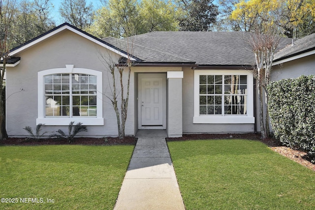 single story home with roof with shingles, a front yard, and stucco siding