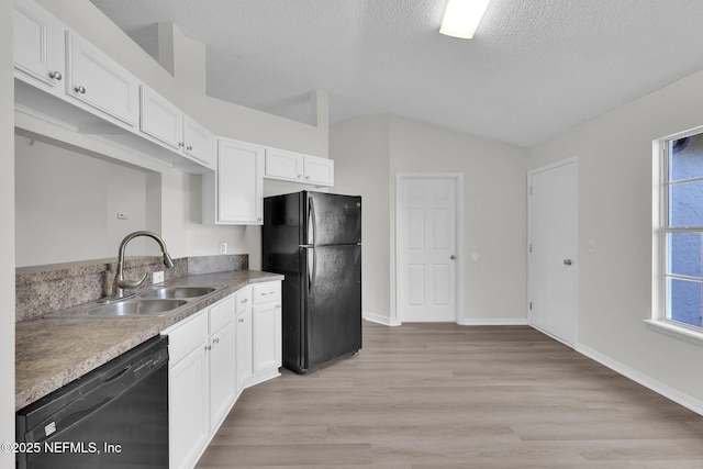 kitchen featuring light wood-style flooring, white cabinets, vaulted ceiling, a sink, and black appliances