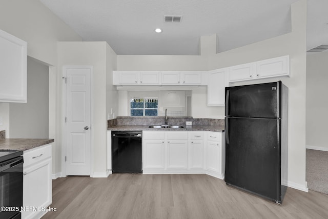 kitchen featuring a sink, visible vents, white cabinetry, black appliances, and light wood finished floors