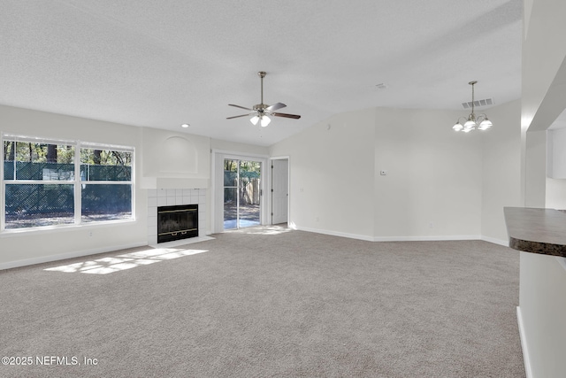 unfurnished living room featuring a wealth of natural light, a tiled fireplace, carpet flooring, and visible vents