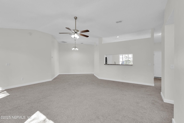 carpeted spare room featuring visible vents, vaulted ceiling, baseboards, and ceiling fan with notable chandelier