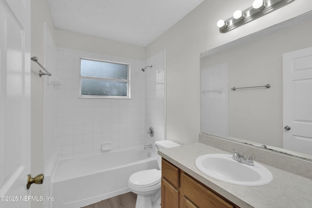 full bath featuring a textured ceiling, toilet, wood finished floors, vanity, and washtub / shower combination