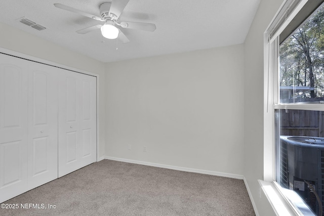 unfurnished bedroom featuring baseboards, visible vents, ceiling fan, carpet floors, and a closet