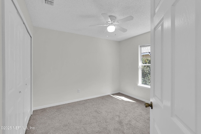 spare room featuring baseboards, visible vents, a ceiling fan, a textured ceiling, and carpet flooring