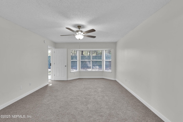 empty room with ceiling fan, a textured ceiling, carpet, and baseboards