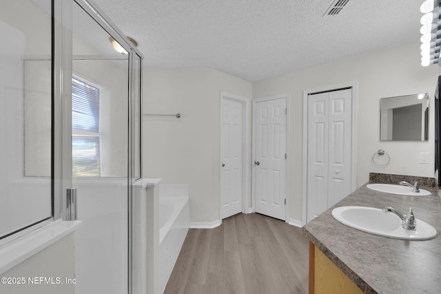 full bath with a garden tub, wood finished floors, a sink, and visible vents