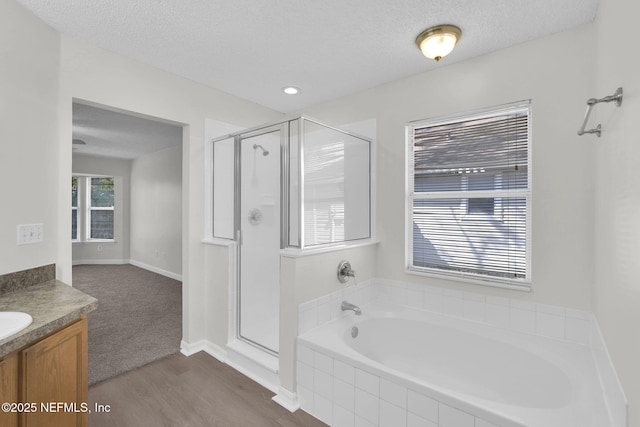 full bath with a shower stall, a textured ceiling, and vanity