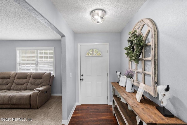 foyer entrance with a textured ceiling, baseboards, wood finished floors, and a textured wall