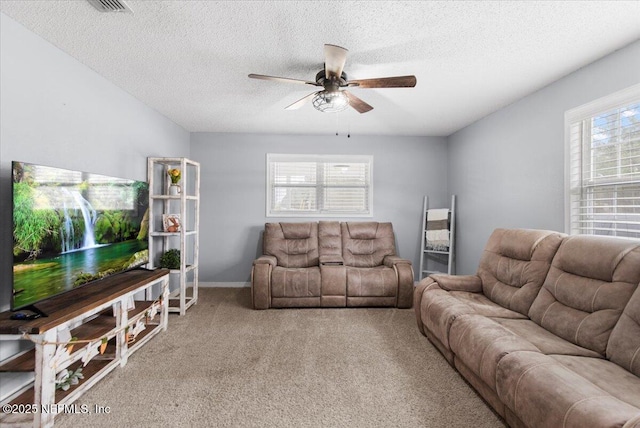 living room featuring ceiling fan, a textured ceiling, carpet, and baseboards