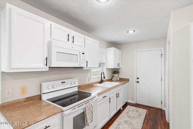 kitchen with white appliances, white cabinets, and a sink