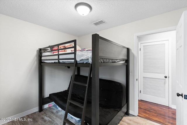 bedroom with visible vents, baseboards, and wood finished floors