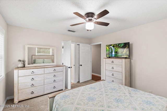 bedroom with light carpet, ceiling fan, visible vents, and a textured ceiling