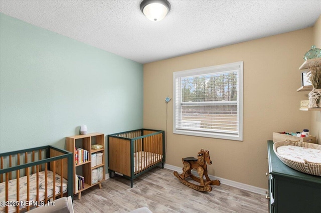 bedroom with a textured ceiling, wood finished floors, and baseboards