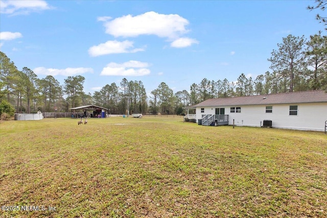 view of yard featuring a detached carport, central AC, and fence