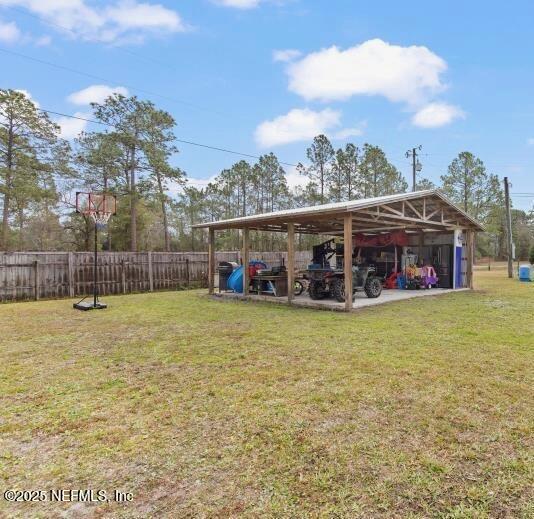 view of parking / parking lot featuring a carport, a pole building, and fence