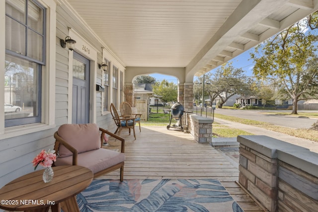 wooden deck featuring a residential view, covered porch, and a grill