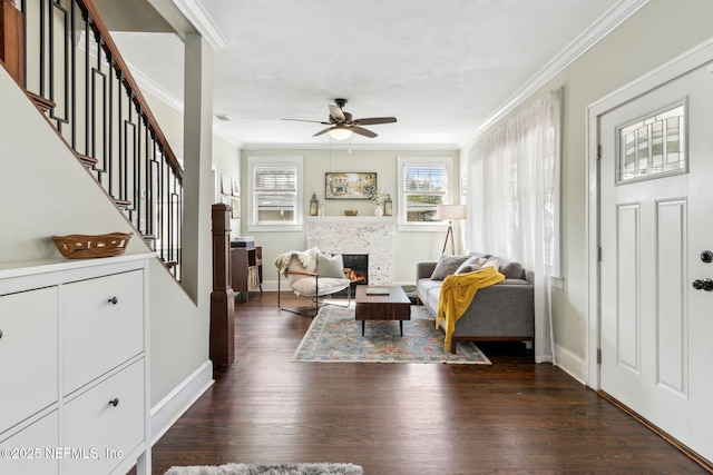 interior space featuring baseboards, stairs, a lit fireplace, ornamental molding, and dark wood finished floors