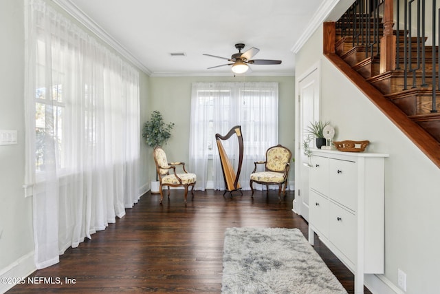 sitting room with ceiling fan, dark wood finished floors, crown molding, and stairs