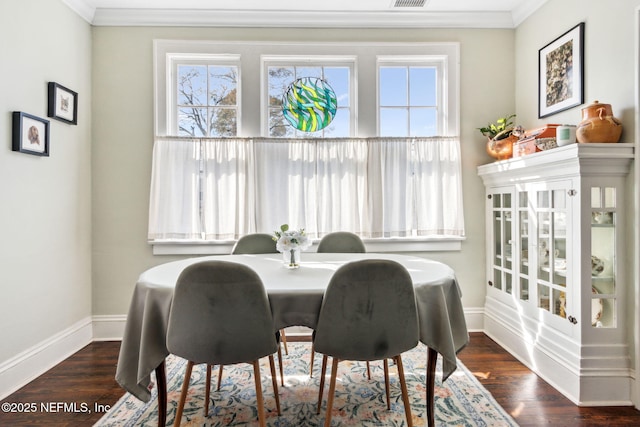 dining room with ornamental molding, wood finished floors, visible vents, and baseboards