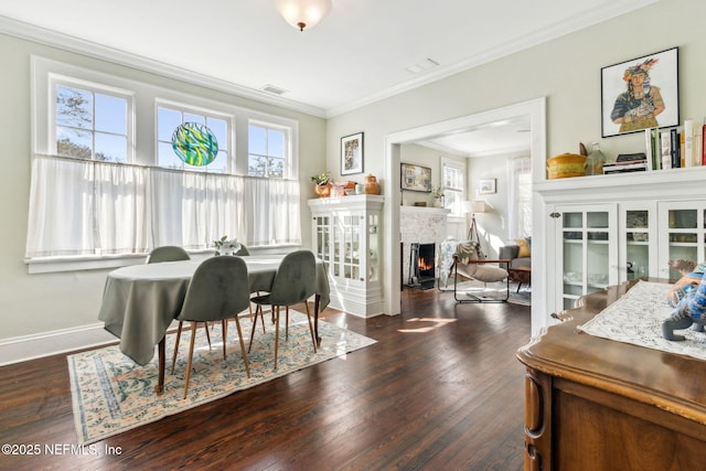 sitting room with a lit fireplace, visible vents, ornamental molding, and wood finished floors